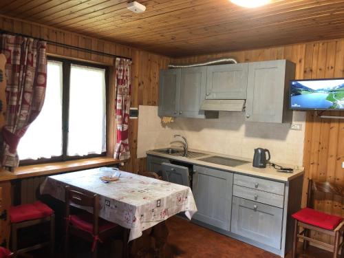 a kitchen with a table and a tv in a cabin at AMPIO MONOLOCALE IN CENTRO CHAMPOLUC in Champoluc