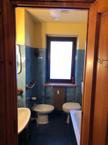 La salle de bains est pourvue de toilettes, d'un lavabo et d'une fenêtre. dans l'établissement AMPIO MONOLOCALE IN CENTRO CHAMPOLUC, à Champoluc