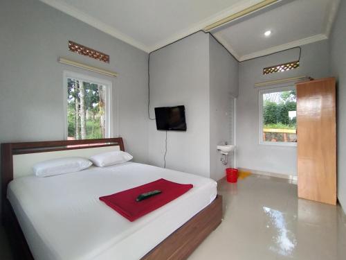 een slaapkamer met een bed met een rode handdoek erop bij Villa Batu Tua Puncak Mitra RedDoorz in Bogor