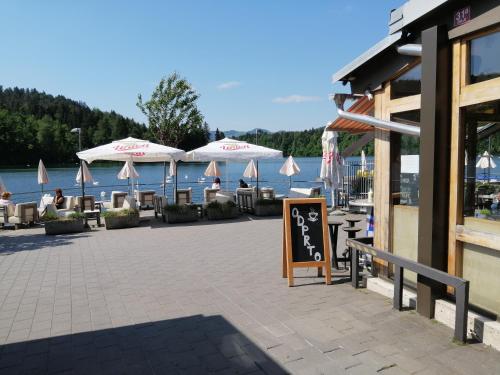 a patio with tables and umbrellas next to the water at Glamping with a view in Smlednik