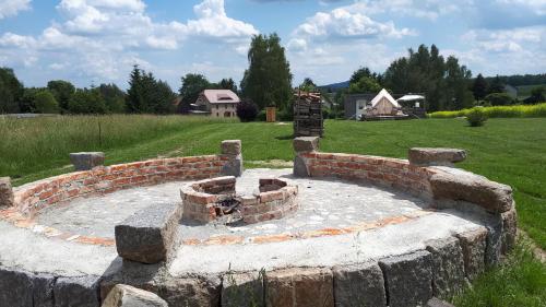 a stone fire pit in a yard with a field at Autark-Camp Gleis A. in Dürrhennersdorf