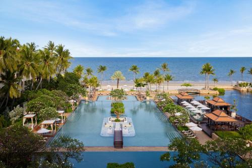 an aerial view of a resort with a pool and the ocean at Dusit Thani Hua Hin in Cha Am
