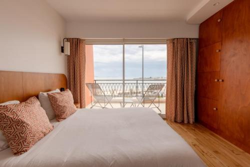 een slaapkamer met een bed en een groot raam bij La Perrinière appartement face mer in Royan