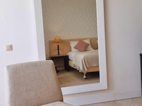 a bedroom with a bed and a chair and a mirror at Marina Smir Hotel & Spa in M'diq