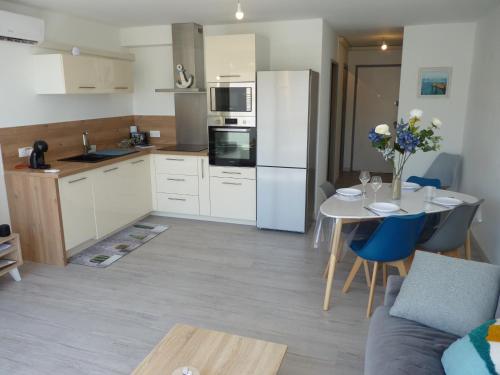 une cuisine avec une table et un réfrigérateur blanc dans l'établissement Sol-y-Days Murènes, Appartement moderne rive droite proche plages et centre, au Grau-du-Roi