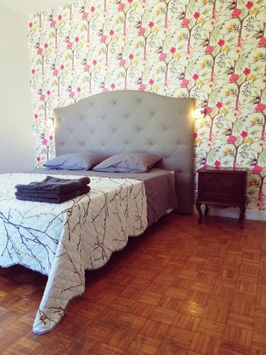 a bedroom with a bed with a white headboard and a wall at Le Logis de la Ferme aux Cerfs in Le Houga