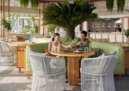 a man and woman sitting at a table in a restaurant at Dusit Thani Hua Hin in Cha Am