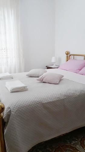 een slaapkamer met een wit bed met roze kussens bij Location Serafina Pennapiedimonte in Pennapiedimonte