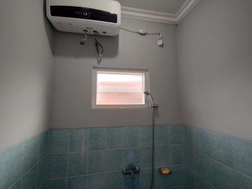 een badkamer met een douche en een televisie aan de muur bij Villa Batu Tua Puncak Mitra RedDoorz in Bogor