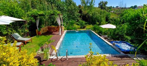a swimming pool in a yard with chairs and umbrellas at Casa da Benfeitoria in Guimarães
