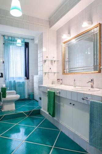 a bathroom with two sinks and a toilet and green floors at Villa del Golfetto in Plemmirio