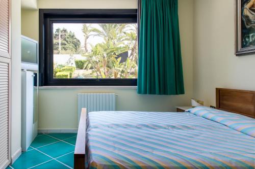a bedroom with a bed and a large window at Villa del Golfetto in Plemmirio