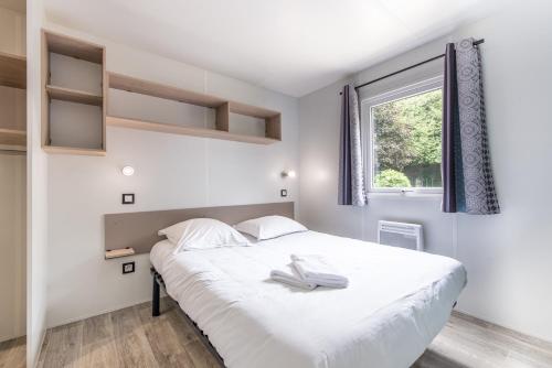 una camera da letto con un letto bianco e una finestra di Les Mobil-homes By Le Marintan a Saint-Michel-de-Maurienne
