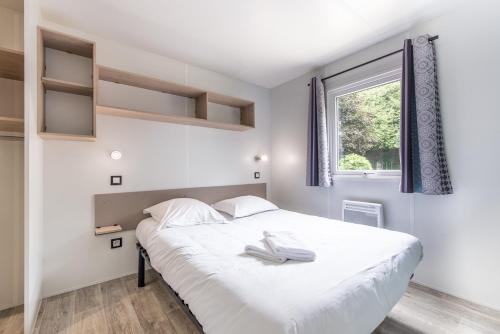 a bedroom with a white bed and a window at Les Mobil-homes By Le Marintan in Saint-Michel-de-Maurienne