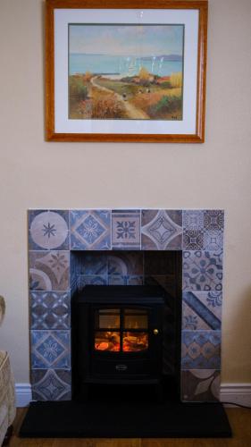 a fireplace with a picture on the wall with a fire place at Horizon View Portstewart Tourist Board approved in Portstewart