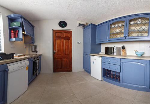 a large kitchen with blue cabinets and a door at Horizon View Portstewart Tourist Board approved in Portstewart