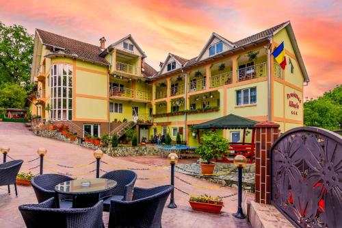 a hotel with tables and chairs in front of a building at Pensiunea Mihaela in Novaci