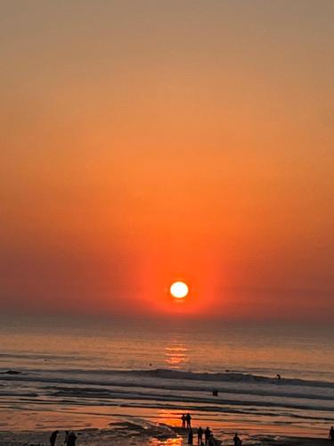 um pôr do sol na praia com pessoas caminhando na praia em Porthtowan Studio em Porthtowan