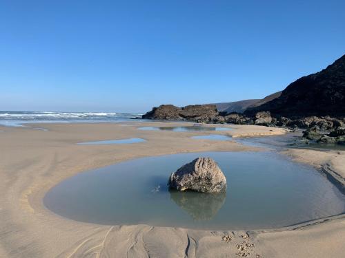 una roca en una piscina de agua en una playa en Porthtowan Studio en Porthtowan