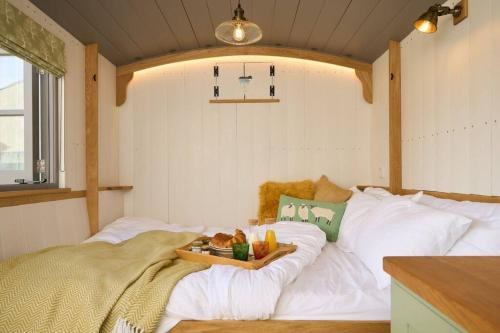 a room with a white couch with a tray of food on it at Luxury Shepherd Hut on small South Hams farm, Devon in Modbury