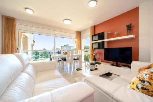 sala de estar con sofá blanco y TV en Hauzify I Apartament Cala Pepo, en L'Ametlla de Mar