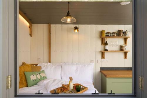 ModburyにあるLuxury Shepherd Hut on small South Hams farm, Devonの白いベッド1台、テーブル、カウンターが備わる客室です。