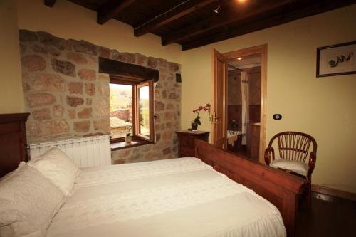 1 dormitorio con 1 cama grande y pared de piedra en La Galana en Nestar