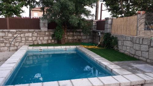 a swimming pool in a yard with a stone wall at Casa rural El Abuelo Arturo in Becerril de la Sierra