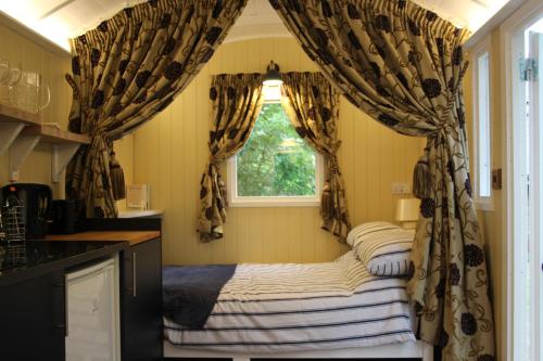 a room with a bed in a kitchen with a window at The Tawny Shepherd Hut, Whitehouse Farm in Stowmarket