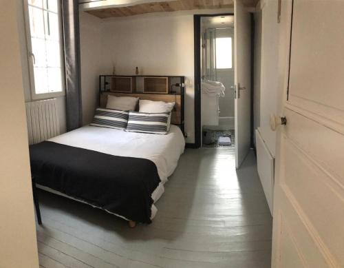 1 dormitorio con 1 cama con almohadas blancas y negras en Chalet basque 6 couchages centre ville Biarritz en Biarritz