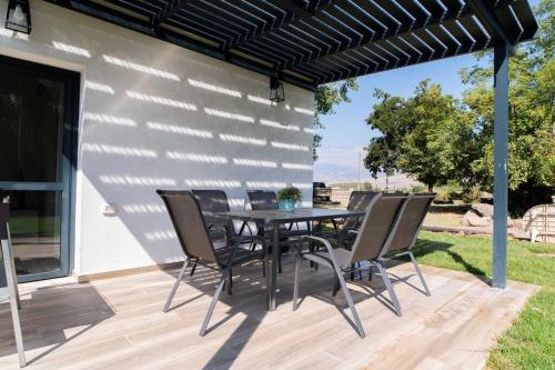 a patio with a table and chairs under a pergola at אצל אהרונ'ק Aronek's Place in ‘Amir