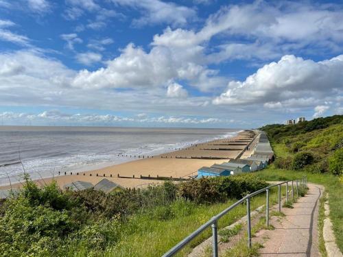 a beach with a long line of umbrellas at La Casita - Inside the Gates of Frinton-On-Sea in Frinton-on-Sea