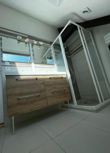 La salle de bains est pourvue d'un miroir et d'une commode en bois. dans l'établissement Le Clos de Baron sur Odon, un havre de paix., à Baron-sur-Odon