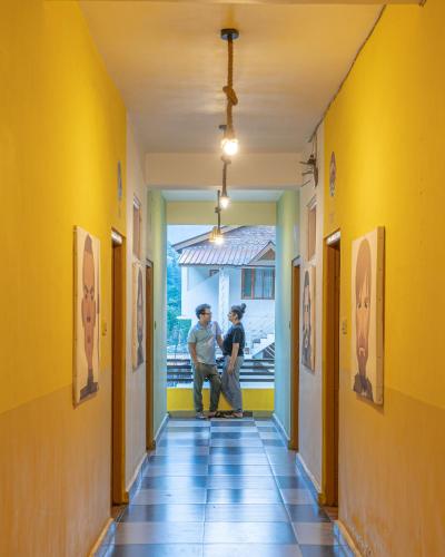 two people standing in a hallway looking at paintings at Whoopers Hostel Kasol in Kasol
