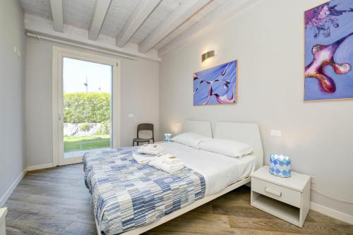 - une chambre blanche avec un lit et une fenêtre dans l'établissement My Peschiera Family Home Fornaci 1, à Peschiera del Garda