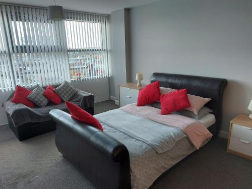 a bedroom with a bed with red pillows and a couch at City Centre Penthouse Apartment in Sunderland