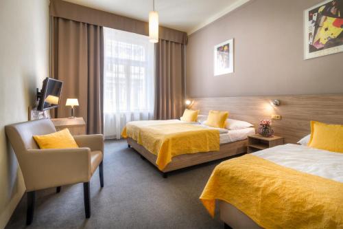 a hotel room with two beds and a chair at Atlantic Hotel in Prague