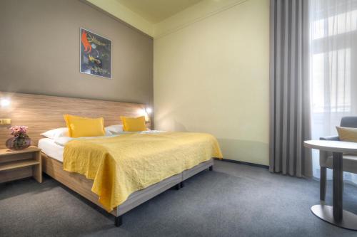a bedroom with a bed with yellow sheets and a window at Atlantic Hotel in Prague