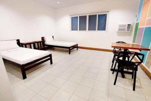 a room with two beds and a table and chairs at Nacho Hostel Cebu in Bulacao