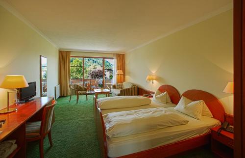 a hotel room with two beds and a desk at Hotel Birkenhof am See in Sankt Kanzian