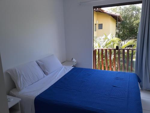Schlafzimmer mit einem blauen und weißen Bett und einem Balkon in der Unterkunft Sol, mar e natureza perto de você. in Itacimirim