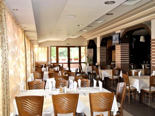 une salle à manger avec des tables blanches et des chaises en bois dans l'établissement Spa Hotel Ivelia, à Dŭbnitsa