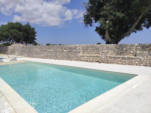 a swimming pool in front of a stone wall at Agriturismo Fondo Paliemmu in Modica