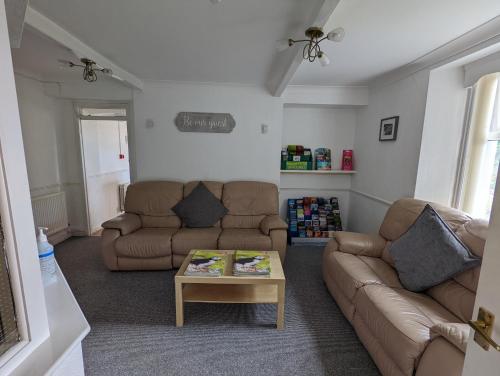 a living room with two couches and a coffee table at Cottage Court Hotel in Tenby