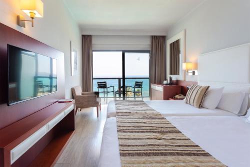 a hotel room with a bed and a flat screen tv at Marins Suites - Adults Only Hotel in Cala Millor