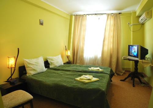 a hotel room with a green bed and a window at Curtea Brancovenească in Constanţa