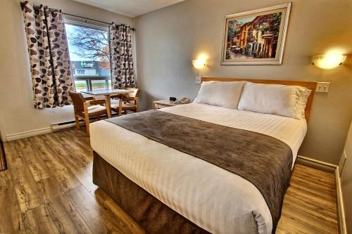 a hotel room with a bed and a table and a window at Hotel-Motel La Difference in Sainte-Marie