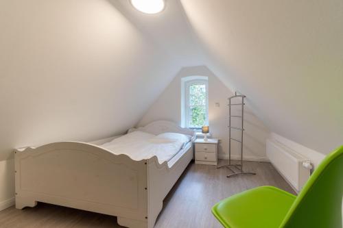 ヴィーク・アウフ・フェールにあるHaus am Leuchtturm Wohnung 3のベッドルーム(白いベッド1台、緑の椅子付)