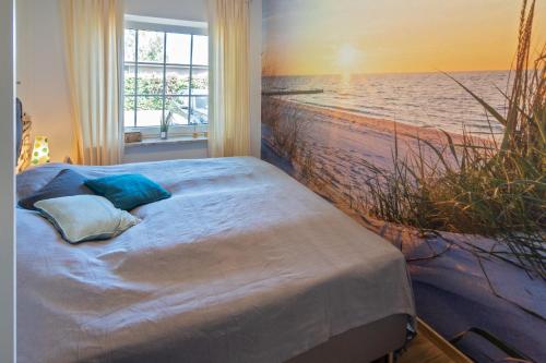 1 dormitorio con 1 cama y una pintura del océano en Hannos Huus, en Nessmersiel