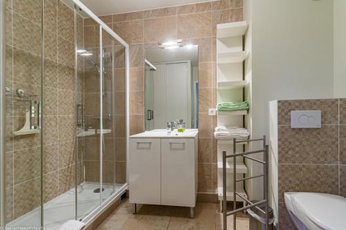 Un baño con ducha, lavabo y espejo. en Résidence Egalité - Montmartre, en Dijon